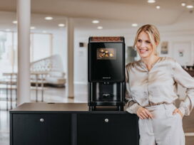 Frau neben Kaffeeautomaten-Modell Barista Compact